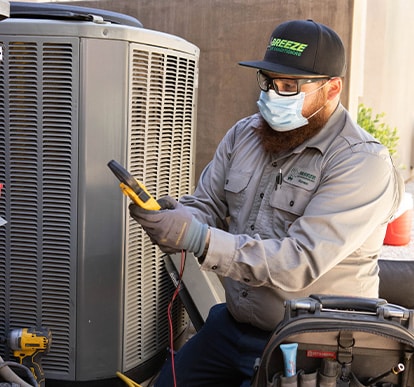 Breeze Air Conditioning employee servicing air conditioning unit